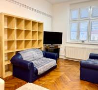 REZERVOVANÉ Na prenájom 3 izbový byt, 73 m2, Bratislava, Zochova - Obývačka v 3-izbovom byte s pohovkami, TV a podlahou s dreveným dekorom.