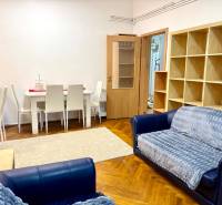 REZERVOVANÉ Na prenájom 3 izbový byt, 73 m2, Bratislava, Zochova - Obývačka v 3-izbovom byte s lavicou, jedálenským stolom a regálom, podlaha s dreveným dekorom.