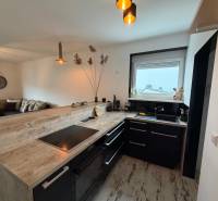 Zariadený 3 izbový byt s balkónom v Kittsee  - Kuchyňa s čiernym nábytkom, barovým pultom a podlahou s dreveným dekorom v 3-izbovom byte.