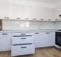 KRÁSNY NOVOZREKONŠTRUOVANÝ 3IB, SNP,POVAŽSKÁ BYSTRICA - Kuchyňa v 3-izbovom byte s bielymi skrinkami a podlahou s dreveným dekorom.