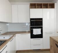 PRENÁJOM –  1 izba (príp. 2 izby) v 3-izb. byte, Gwerkovej ul., BA V - Moderná kuchyňa s bielymi skrinkami a podlahou s dreveným dekorom v 3-izbovom byte.