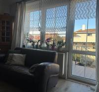 PREDAJ : RODINNÝ DOM, KOMÁRNO - Kožená sedačka a okno s čipkovanými závesmi v Rodinnom dome s podlahou s dreveným dekorom.