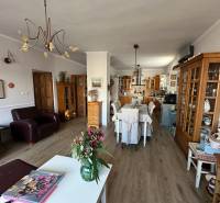 PREDAJ : RODINNÝ DOM, KOMÁRNO - Obývacia izba s kuchyňou v rodinnom dome, podlaha s dreveným dekorom, kvetiny na stole.
