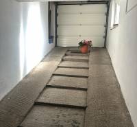 PREDAJ : RODINNÝ DOM, KOMÁRNO - Garáž v rodinnom dome s betónovou rampou a kvetináčom pri stene.