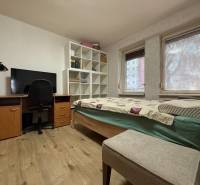 PREDAJ - 2i BYT - ZLATÉ MORAVCE - Izba v 2-izbovom byte s posteľou, pracovným stolom a podlahou s dreveným dekorom.