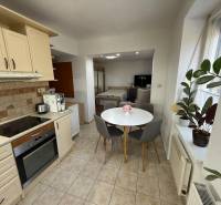 PREDAJ - 2i BYT - ZLATÉ MORAVCE - Kuchyňa v 2-izbovom byte s okrúhlym stolom, rastlinami a spotrebičmi.