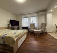 PREDAJ - 2i BYT - ZLATÉ MORAVCE - Spálňa v 2-izbovom byte s podlahou s dreveným dekorom a pohodlnými kreslami.