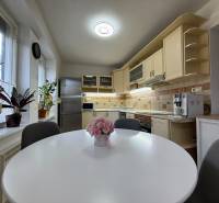 PREDAJ - 2i BYT - ZLATÉ MORAVCE - Kuchyňa v 2-izbovom byte s kuchynskou linkou, oknami a rastlinami.