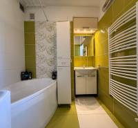 PREDAJ - 2i BYT - ZLATÉ MORAVCE - Kúpeľňa v 2-izbovom byte so zelenými obkladmi, vaňou a moderným vykurovacími telesom.