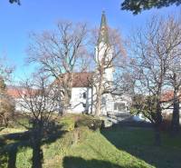 LIMBACH, 176 m2 –  kompletne zrekonštruovaný 5-i rodinný dom - Starý kostol s vežou, stromy bez listov, okolie s trávnatým porastom.