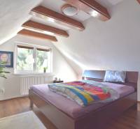 LIMBACH, 176 m2 –  kompletne zrekonštruovaný 5-i rodinný dom - Podkrovná spálňa s drevenými trámami, veľkým oknom a posteľou, priestor Limbach dom.
