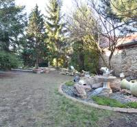 LIMBACH, 176 m2 –  kompletne zrekonštruovaný 5-i rodinný dom - Záhrada pri rodinnom dome, Limbach, so zeleňou, kamennými dekoráciami a starou kamennou stenou.