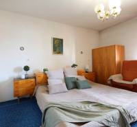 RD v jednej z najžiadanejších lokalít Michaloviec – pod Hrádkom - Spálňa s veľkou posteľou, drevenými skrinkami a kreslom v rodinnom dome.