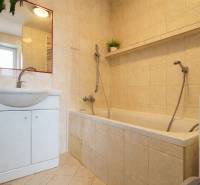 REZERVONY - 2 izbový tehlový byt na Novej Dubnici, 60  - Kúpeľňa v 2-izbovom byte s vaňou, umývadlom, zrkadlom a béžovými obkladmi.