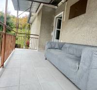 Prerobený rodinný dom na veľkom tichom pozemku v obci Pruské   - Terasa rodinného domu v Pruskom s pohovkou a výhľadom na zeleň.