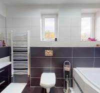 Prerobený rodinný dom na veľkom tichom pozemku v obci Pruské   - Kúpeľňa v rodinnom dome s vaňou, dlaždicami, umývadlom a oknami na stene.