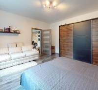 Prerobený rodinný dom na veľkom tichom pozemku v obci Pruské   - Spálňa v rodinnom dome s priestrannou skriňou a podlahou s dreveným dekorom.