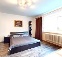 Prerobený rodinný dom na veľkom tichom pozemku v obci Pruské   - Spálňa v rodinnom dome s posteľou, skrinkou, obrazom a podlahou s dreveným dekorom.