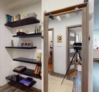 Prerobený rodinný dom na veľkom tichom pozemku v obci Pruské   - Interiér rodinného domu s otvoreným priechodom, knihovničkou a dreveným dekorom podlahy.