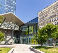 Slnečný 2i byt, pivnica, internet v cene, Nivy, Niťová ul. - Exteriér obchodného centra v Bratislave s modernou architektúrou a zelenou plochou.