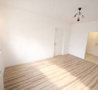 Rezervovaný/ Na predaj 2-izb. byt s loggiou, Senica, Paláriková ul. - Izba v 2-izbovom byte s podlahou s dreveným dekorom a svietidlom.