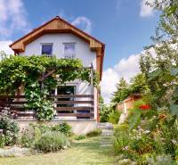 3D, Predaj novostavba, celoročne obývateľná chata, Stupava, Ovocinár - Chata v Stupave s bohatou zeleňou a kvitnúcimi kvetmi v záhrade.