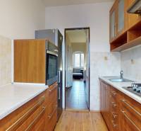 3-izbový byt s extrémne nízkymi nákladmi v Michalovciach - Kuchyňa v 3-izbovom byte s podlahou s dreveným dekorom a svetlými obkladmi.