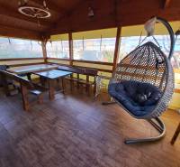 Predáme záhradu so zrubovou chatou, Nitra - Dolné Krškany - Oáza pokoja so závesným kreslom a dreveným nábytkom na podlahe s dreveným dekorom v Záhradách.