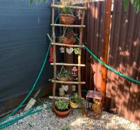 Predáme záhradu so zrubovou chatou, Nitra - Dolné Krškany - Záhrady v Dolných Krškanoch v Nitre s ozdobným rebríkom a kvetináčmi na štrkovom podklade.