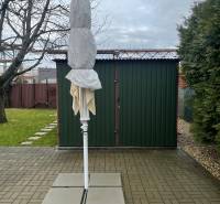 Predáme záhradu so zrubovou chatou, Nitra - Dolné Krškany - Záhrady v Dolných Krškanoch v Nitre s poskladaným slnečníkom, spevnenou plochou a trávnikom.