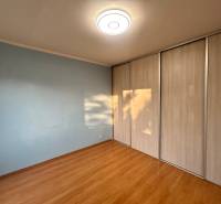 Predaj 3 izb. bytu s balkónom v NZ - Izba s podlahou s dreveným dekorom a vstavanou skriňou v 3-izbovom byte.