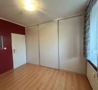 Predaj 3 izb. bytu s balkónom v NZ - Izba v 3-izbovom byte s podlahou v drevenom dekore a vstavanou skriňou.