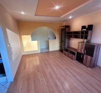 Predaj 3 izb. bytu s balkónom v NZ - Obývacia izba v 3-izbovom byte s podlahou s dreveným dekorom a vstavaným osvetlením.