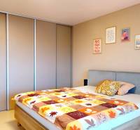 Novozariadený rodinný dom s veľkými spálňami i šatníkom pri Trenčíne   - Spálňa v rodinnom dome s posteľou, vstavanou skriňou a dekoratívnymi obrazmi na stene.