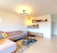 Novozariadený rodinný dom s veľkými spálňami i šatníkom pri Trenčíne   - Obývačka v rodinnom dome s rohovou sedačkou, okrúhlymi stolíkmi a podlahou s dreveným dekorom.