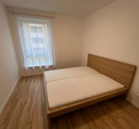 - PRENÁJOM 2-IZ. BYTU S PARKOVACÍM MIESTOM – MILOSLAVOV - Spálňa s posteľou, podlaha s dreveným dekorom v 2-izbovom byte.