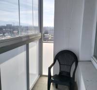 Veľký 2-izbový byt, Martin - Sever - REZERVOVANÉ - Zasklený balkón s výhľadom a plastovou stoličkou, súčasť 2-izbového bytu.