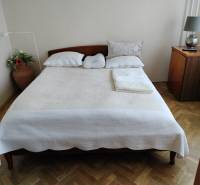 2 izbový byt na Severe - Spálňa s manželskou posteľou, podlahou s dreveným dekorom a nočným stolíkom v 2-izbovom byte.