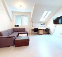 Na prenájom zariadené kancelárie v centre mesta Holíč - Kancelárie s podlahou s dreveným dekorom, stôl, sedačka a obrazovka na stene.