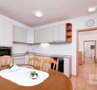 Nové v ponuke | 3-izbový byt 91 m² | 2× balkón | parkovanie | RUSTICA  - Jedáleň v 3-izbovom byte s kuchynskou linkou a podlahou s dreveným dekorom.