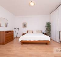 Nové v ponuke | 3-izbový byt 91 m² | 2× balkón | parkovanie | RUSTICA  - Spálňa s posteľou, komodou a podlahou s dreveným dekorom v 3-izbovom byte.