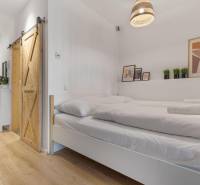 - PREDAJ - APARTMÁN - 38 m2 + 14 m2 LOGGIA - TEHELNÉ POLE - Spálňa v 1-izbovom byte s posuvnými dverami a podlahou s dreveným dekorom.