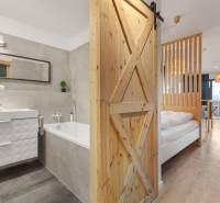 - PREDAJ - APARTMÁN - 38 m2 + 14 m2 LOGGIA - TEHELNÉ POLE - Interiér 1-izbového bytu s vaňou a podlahou s dreveným dekorom.