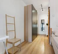 - PREDAJ - APARTMÁN - 38 m2 + 14 m2 LOGGIA - TEHELNÉ POLE - Interiér 1-izbového bytu s podlahou s dreveným dekorom, skriňou a posteľou.