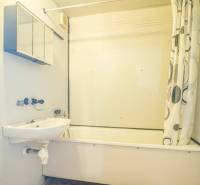 Prenájom 2-izbového bytu v Poprade na Dostojevského ul. - Kúpeľňa s vaňou a sprchovým závesom v 2-izbovom byte, svetlé steny, oranžová podlaha.