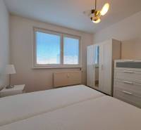 Prenájom 2-izbového bytu v Poprade na Dostojevského ul. - Spálňa v 2-izbovom byte s bielym nábytkom a posteľou, okno s žalúziami.