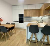 PRENÁJOM luxusný 2 izbový byt v centre mesta Nitra, parkovanie - Kuchyňa v 2-izbovom byte s podlahou s dreveným dekorom, jedálenským stolom a barovým pultom.