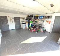 Zabehnutá novostavba: Komfort domu, pokoj vidieka a na skok do BB a ZV - Garáž v rodinnom dome s náradím a skladovacími policami, podlaha z keramických dlaždíc.