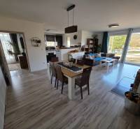 Zabehnutá novostavba: Komfort domu, pokoj vidieka a na skok do BB a ZV - Obývacia izba rodinného domu s otvorenou kuchyňou a podlahou s dreveným dekorom.