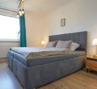 Rezervované -  3i byt v Nemšovej s loggiou po rekonštrukcii - 74m²  - Spálňa v 3-izbovom byte s posteľou, nočnými stolíkmi a podlahou s dreveným dekorom.